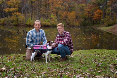 Steve and Riley Jones pose with Riley's dog, Sophie, in front of a pond.